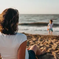 Mother watching her children enjoying the beach